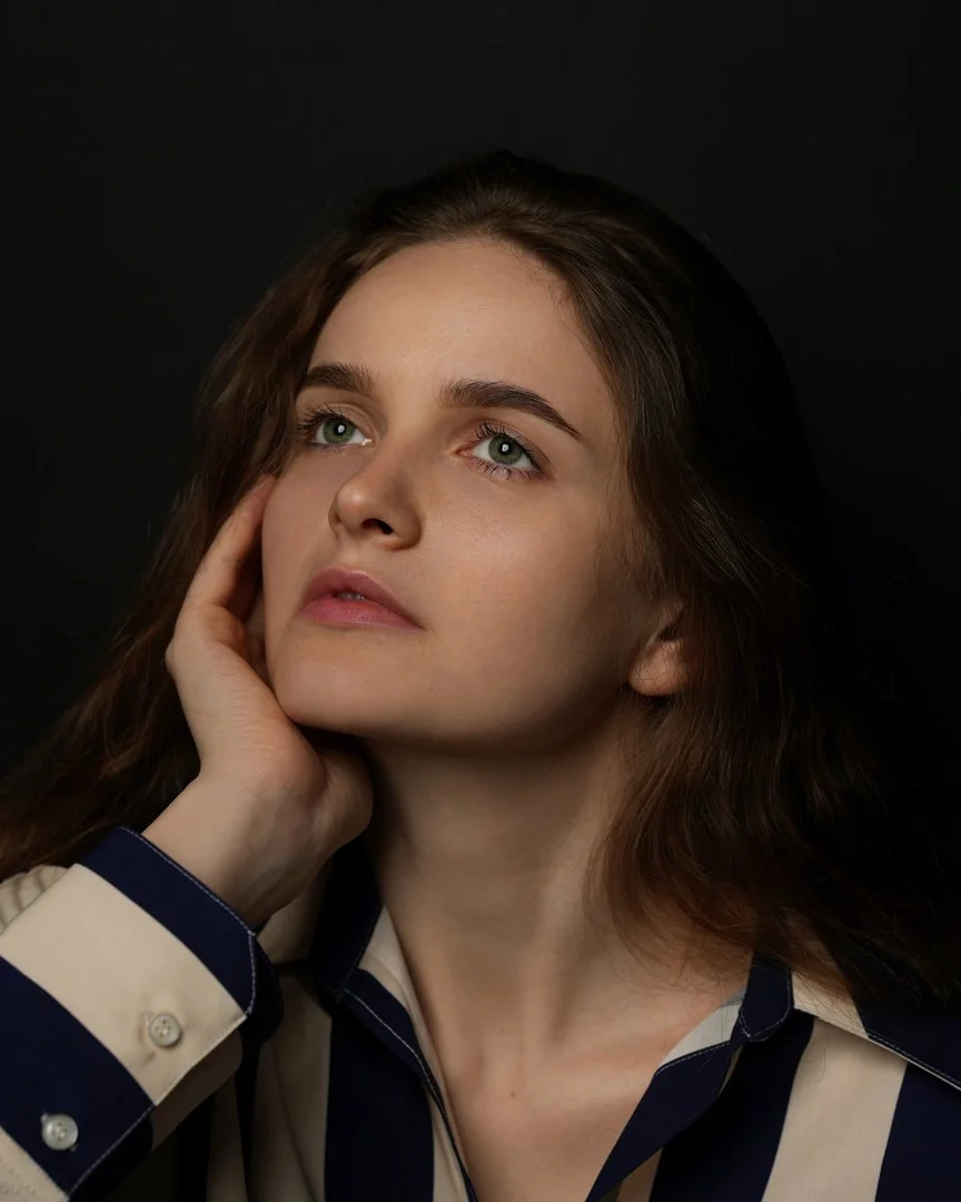 Portrait of Kate Zotova with her hand on her face against a dark background in Cupertino, California