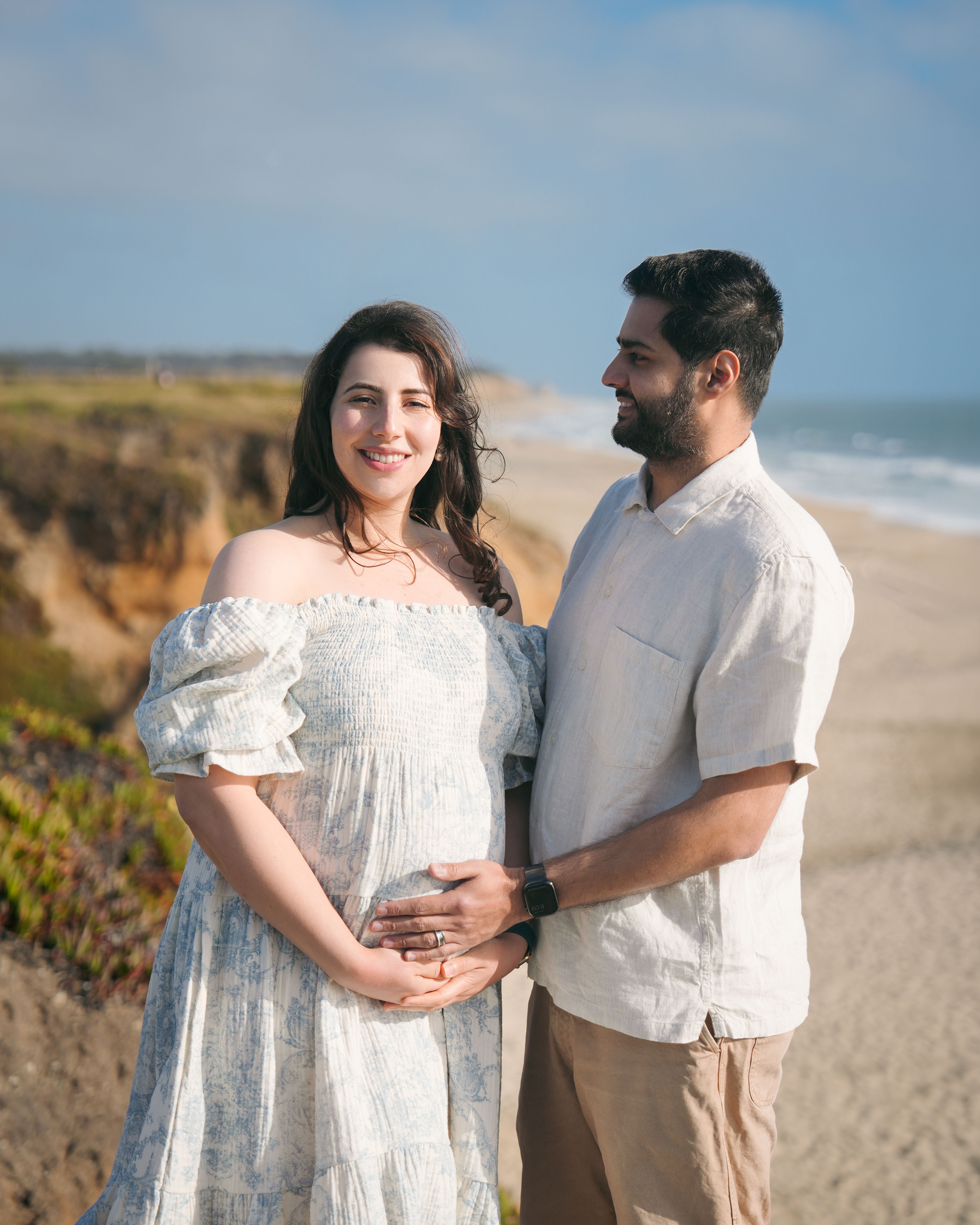 Smiling maternity couple on a bluff in Half Moon Bay, California