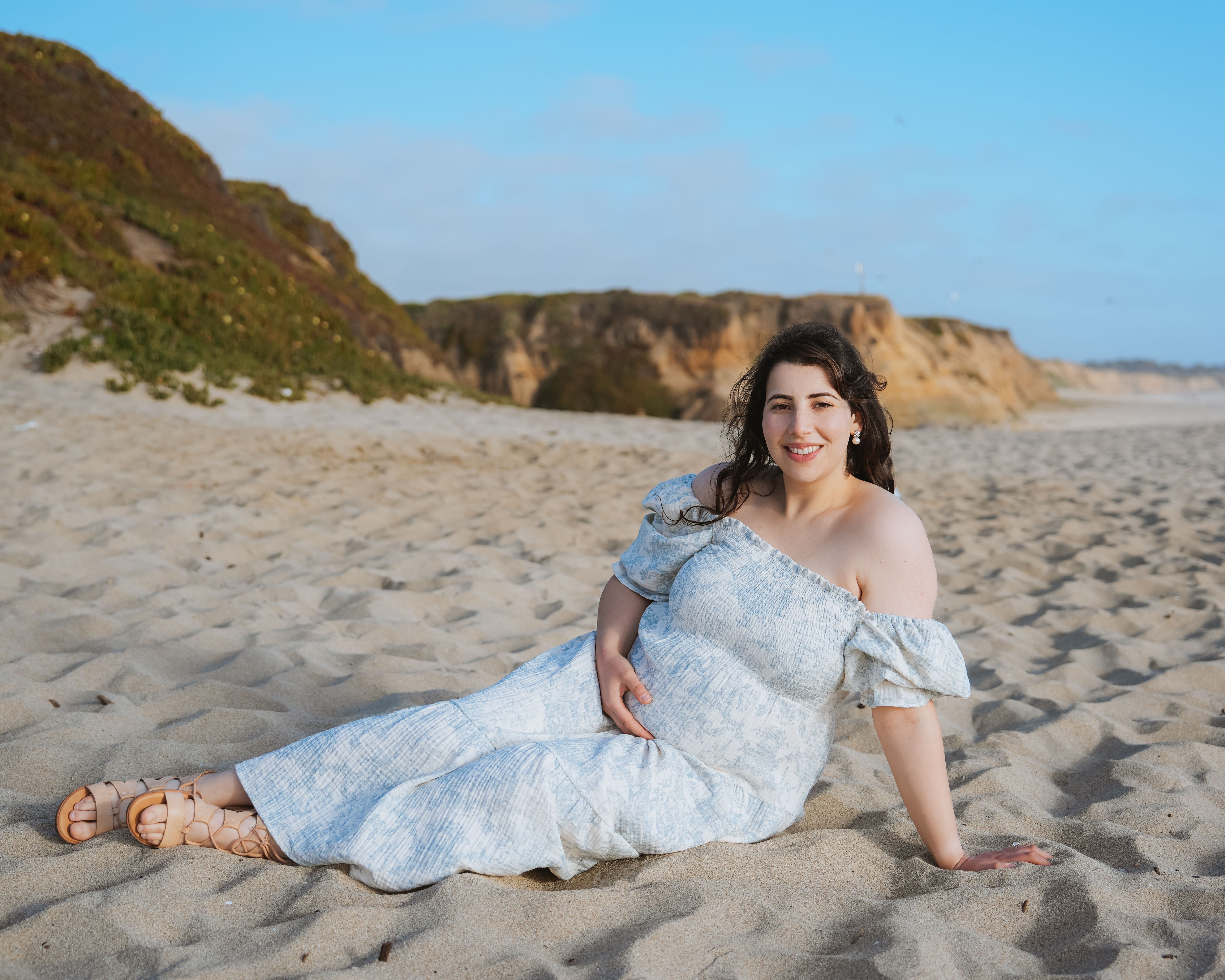 Reclining maternity portrait on a sandy beach in Half Moon Bay, California